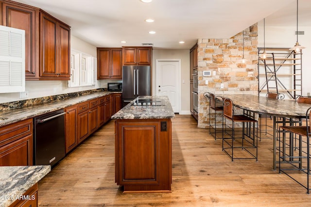 kitchen with black appliances, recessed lighting, a center island, and light wood-style floors