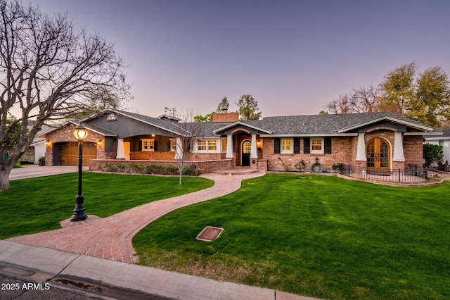 view of front facade featuring an attached garage, brick siding, french doors, decorative driveway, and a front lawn