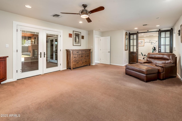 living area with french doors, recessed lighting, visible vents, a barn door, and light carpet