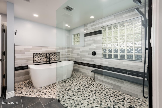 full bathroom featuring a walk in shower, visible vents, tile walls, a freestanding bath, and tile patterned floors