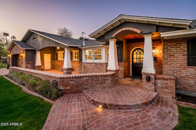 view of front of house featuring a garage, a porch, and brick siding