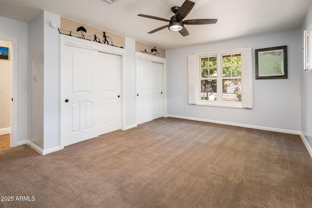 unfurnished bedroom with a ceiling fan, carpet flooring, baseboards, and two closets