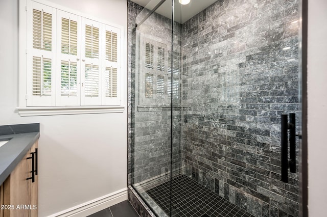 bathroom with tile patterned floors, a shower stall, baseboards, and vanity