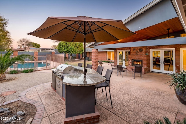 patio terrace at dusk with a fenced in pool, fence, area for grilling, and french doors