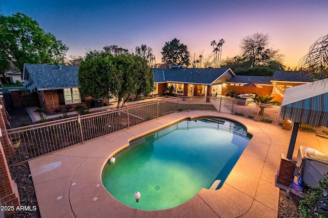 pool at dusk featuring a patio area, fence, and a fenced in pool