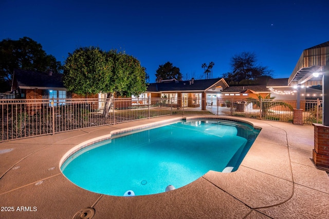 pool at night with fence, a fenced in pool, and a patio