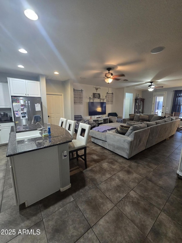 tiled living room featuring ceiling fan and sink