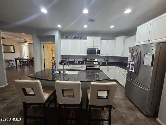 kitchen featuring appliances with stainless steel finishes, sink, an island with sink, and white cabinets