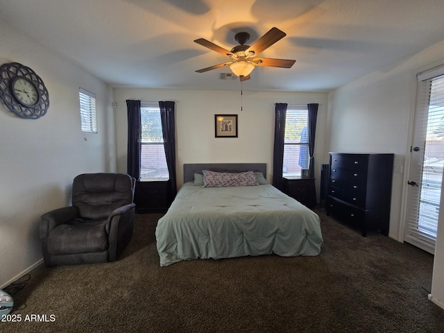 bedroom with multiple windows, ceiling fan, and dark carpet