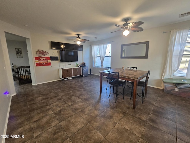 dining space featuring dark tile patterned floors and ceiling fan