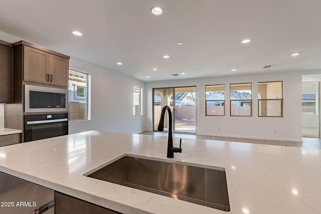 kitchen with black appliances, light stone countertops, and sink