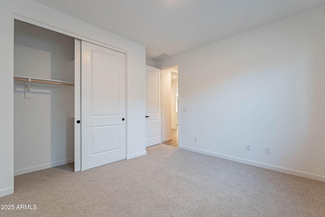 unfurnished bedroom with a closet and light carpet