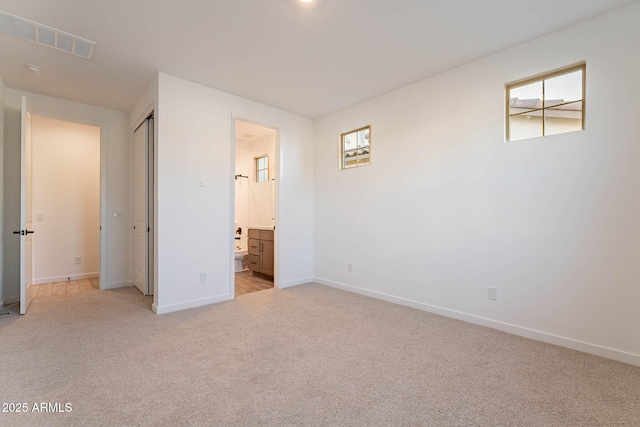 unfurnished bedroom featuring light carpet, a closet, and connected bathroom