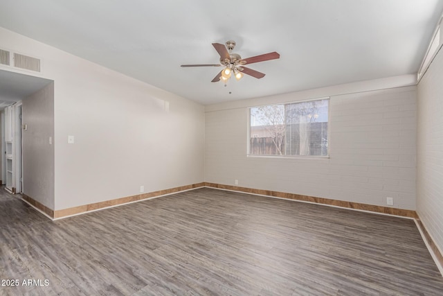 empty room featuring baseboards, ceiling fan, visible vents, and wood finished floors