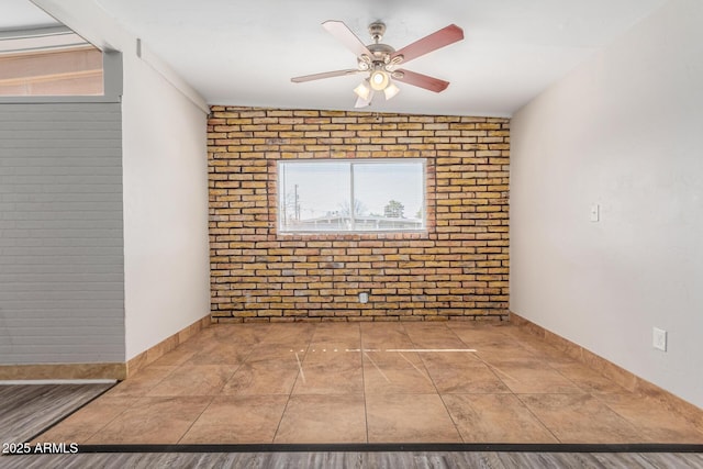 empty room with a ceiling fan, baseboards, and brick wall