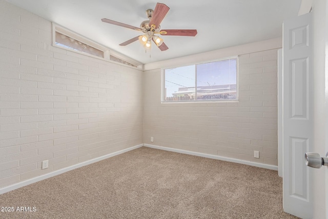 carpeted spare room featuring vaulted ceiling, baseboards, ceiling fan, and brick wall