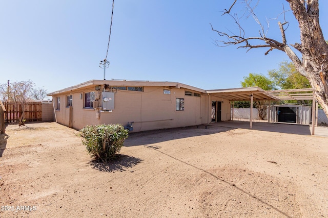 rear view of property with driveway, fence, and a carport