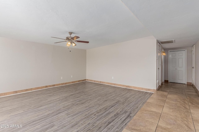 unfurnished room with a ceiling fan, light wood-type flooring, visible vents, and baseboards