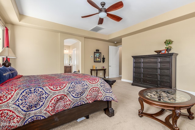 carpeted bedroom with a tray ceiling, ceiling fan, and connected bathroom