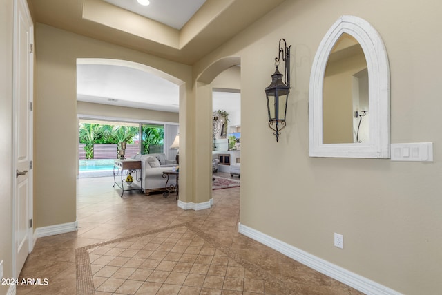 hallway with light tile patterned floors and a tray ceiling