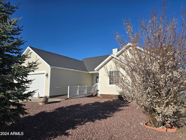 back of property featuring a garage, a shingled roof, and a chimney