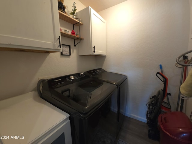 laundry area featuring dark hardwood / wood-style floors, washer and clothes dryer, and cabinets