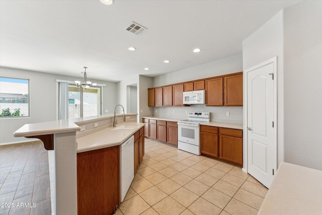 3310 W Chambers St, Phoenix, AZ 85041 - kitchen with white appliances, brown cabinets, a chandelier, light countertops, and recessed lighting