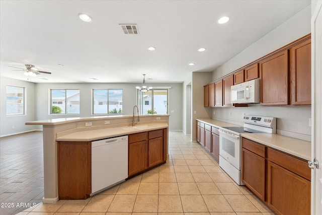 3310 W Chambers St, Phoenix, AZ 85041 - kitchen featuring white appliances, brown cabinetry, light countertops, a center island with sink, and recessed lighting