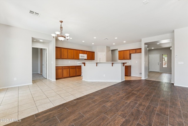 3310 W Chambers St, Phoenix, AZ 85041 - kitchen featuring white microwave, brown cabinetry, a chandelier, recessed lighting, and light countertops