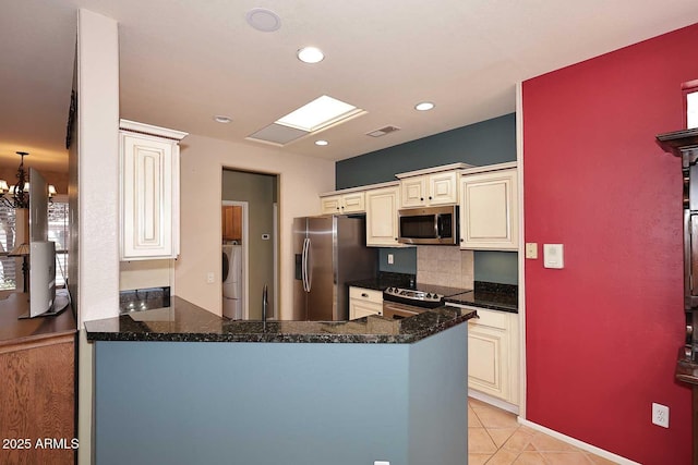 17630 N Somerset Dr, Surprise, AZ 85374 - kitchen featuring appliances with stainless steel finishes, washer / clothes dryer, cream cabinetry, a peninsula, and light tile patterned floors