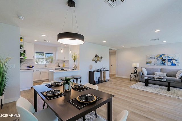 dining space with sink and light wood-type flooring