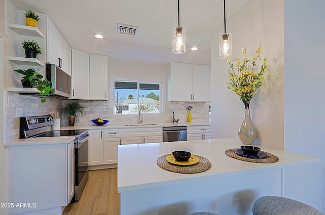 kitchen with pendant lighting, sink, a breakfast bar area, white cabinetry, and stainless steel appliances