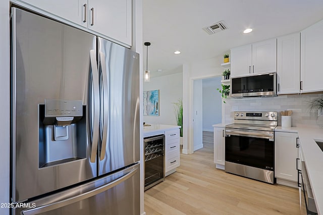 kitchen featuring white cabinets, tasteful backsplash, appliances with stainless steel finishes, and beverage cooler