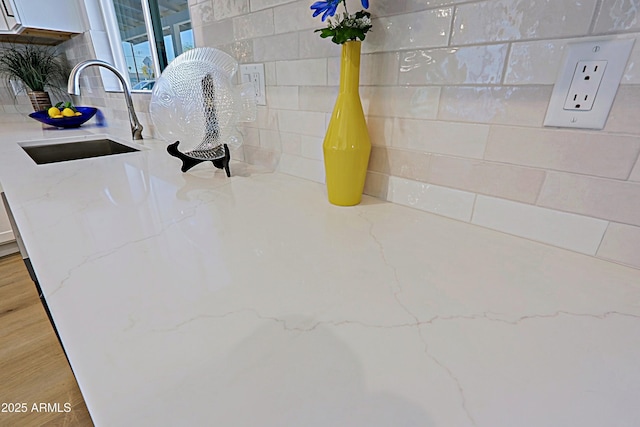 room details featuring light stone countertops, sink, and white cabinets