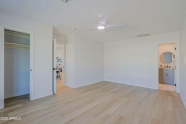 unfurnished bedroom with sink, light hardwood / wood-style flooring, ceiling fan, ensuite bath, and a closet