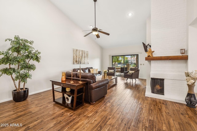 living room with ceiling fan, high vaulted ceiling, dark wood-type flooring, and a fireplace