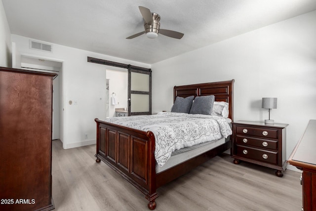 4150 E Cactus Rd Unit 205, Phoenix, AZ 85032 - bedroom featuring light wood-style flooring, a barn door, and a ceiling fan