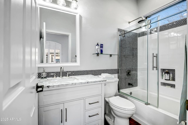 full bath with a healthy amount of sunlight, toilet, vanity, and combined bath / shower with glass door