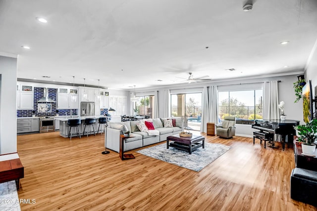 living room featuring a wealth of natural light, crown molding, light wood finished floors, and recessed lighting