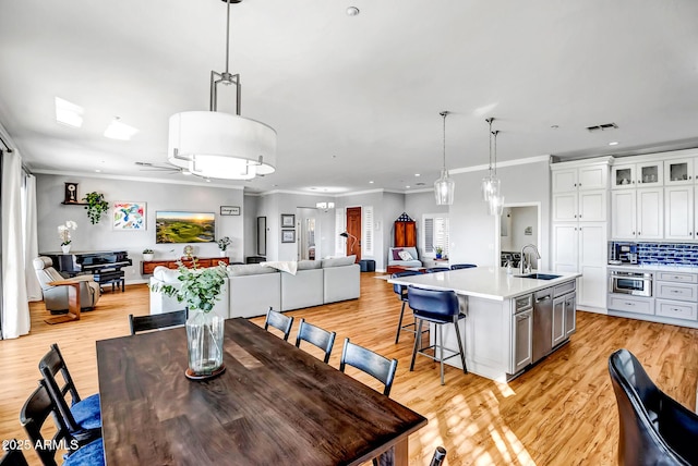 dining area featuring crown molding, sink, ceiling fan, and light hardwood / wood-style flooring