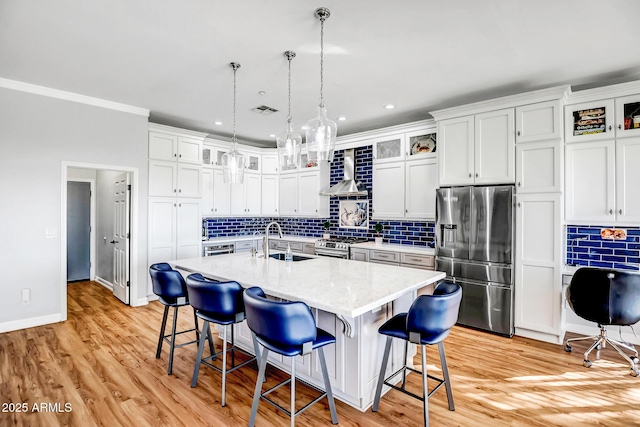 kitchen featuring visible vents, decorative backsplash, wall chimney exhaust hood, stainless steel appliances, and a sink