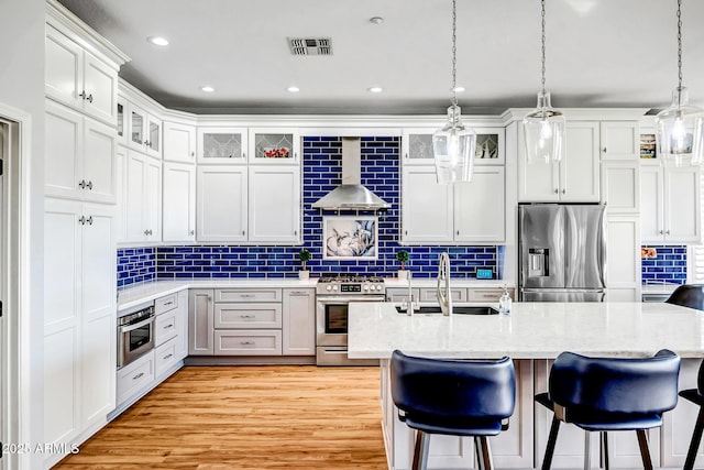 kitchen with visible vents, decorative backsplash, a breakfast bar area, stainless steel appliances, and a sink