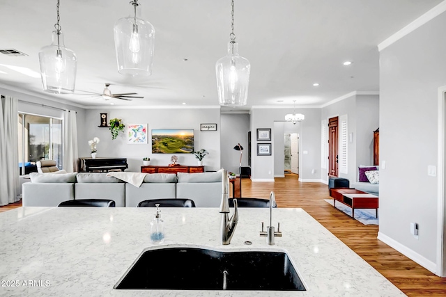 kitchen with visible vents, light wood-style flooring, ornamental molding, open floor plan, and a sink