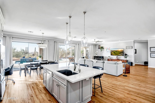 kitchen featuring crown molding, sink, gray cabinets, light wood-type flooring, and an island with sink