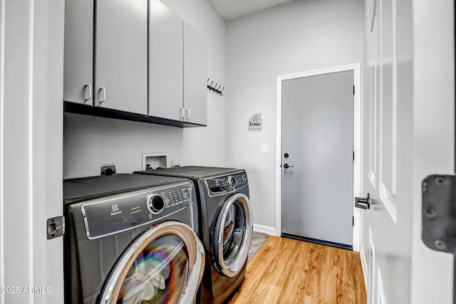 clothes washing area with light wood finished floors, separate washer and dryer, cabinet space, and baseboards