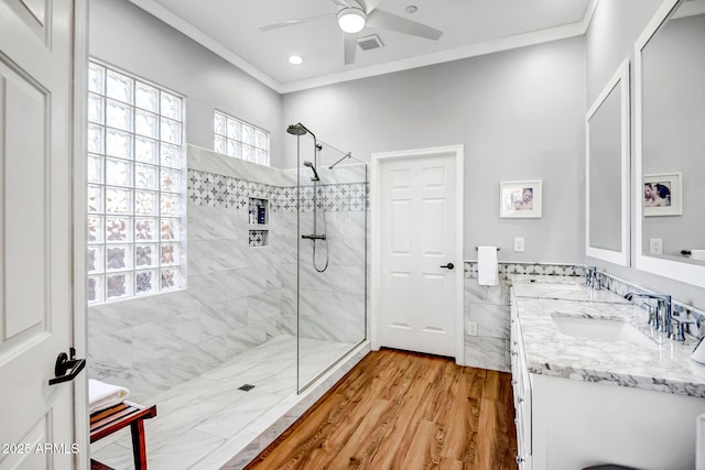 bathroom with tiled shower, vanity, hardwood / wood-style flooring, and ornamental molding