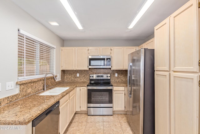 kitchen featuring light stone countertops, sink, stainless steel appliances, decorative backsplash, and light tile patterned floors