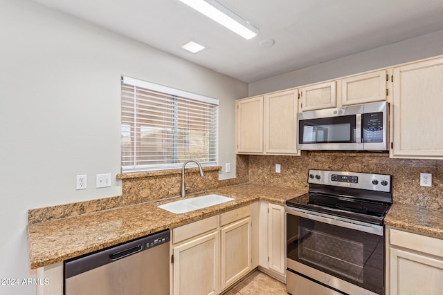 kitchen with light stone countertops, stainless steel appliances, decorative backsplash, and sink