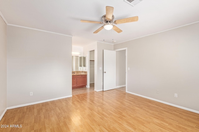 unfurnished bedroom with ensuite bath, ornamental molding, light wood-type flooring, and ceiling fan