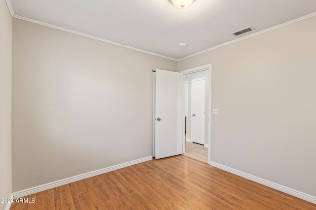 spare room featuring crown molding and light wood-type flooring